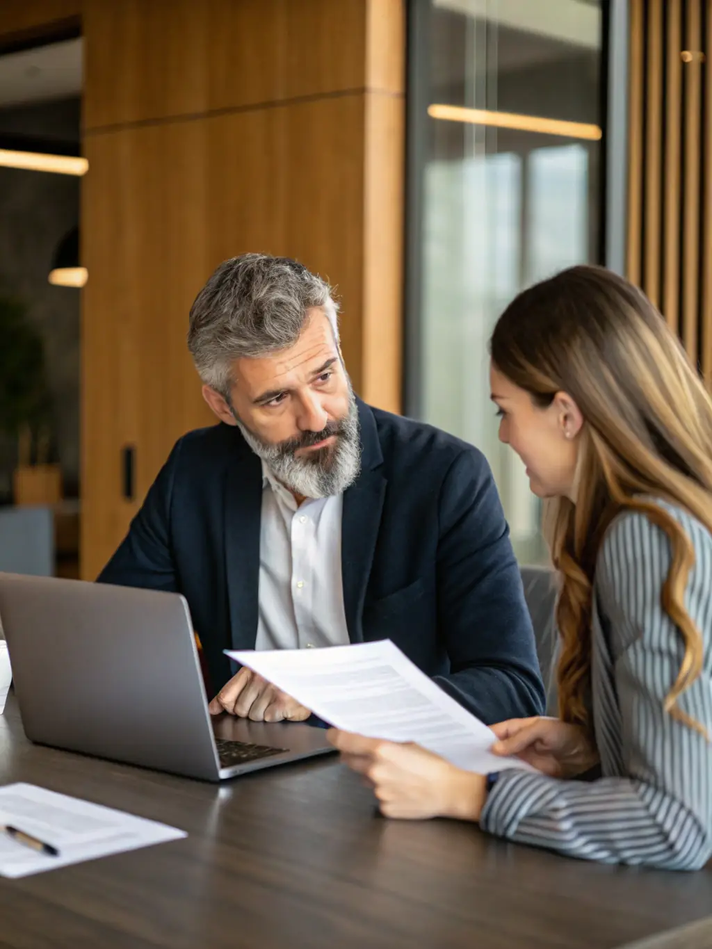 A professional business coach reviewing financial statements with a small business owner in a modern office setting, emphasizing collaboration and strategic planning.
